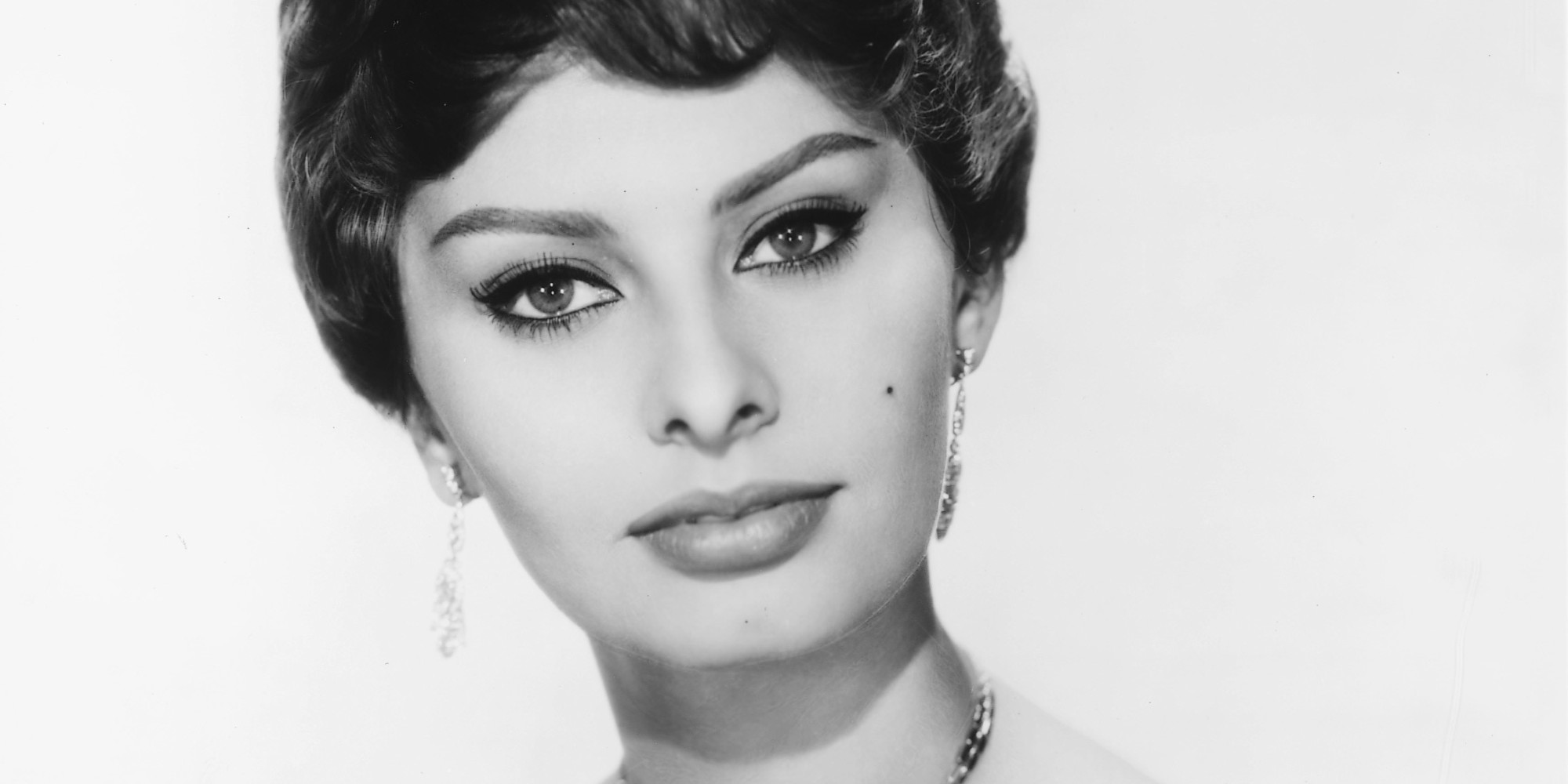 Headshot of Sophia Loren, Italian actress, looking glamorous, wearing a shoulderless dress and a diamond necklace and diamond earrings in a studio portrait, against a white background, circa 1950. (Photo by Silver Screen Collection/Getty Images)